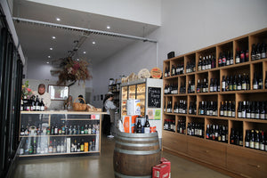 The interior of a wine store with lots of bottles.
